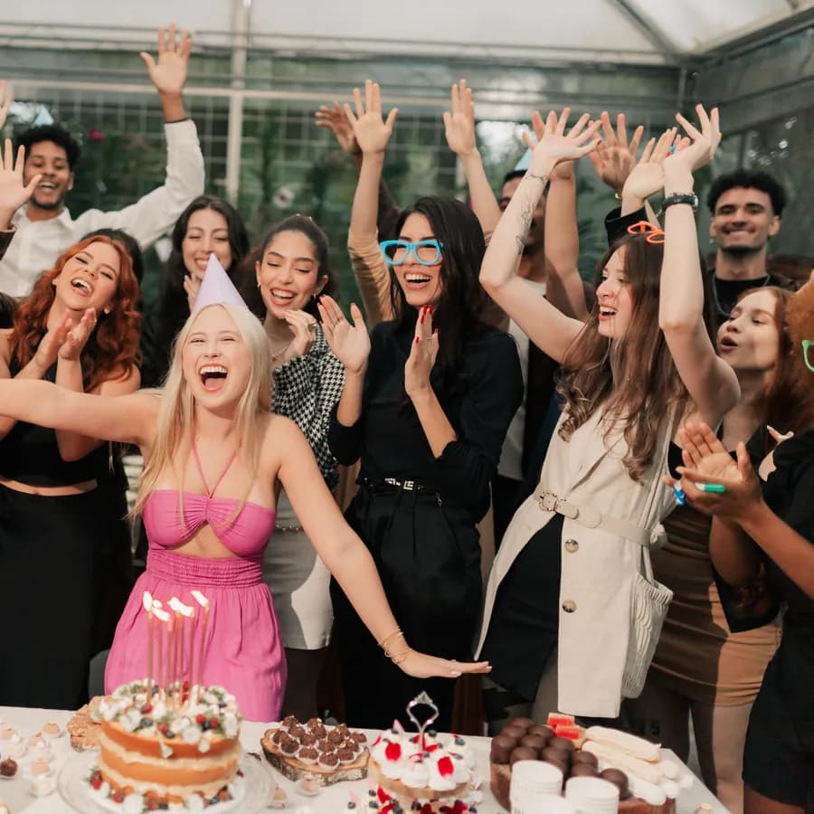 Friends cheering around a birthday cake with lit candles